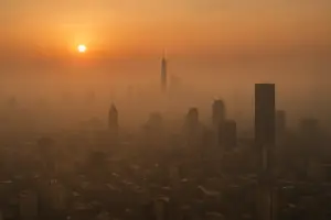City skyline covered in smog and haze at sunset, symbolizing urban air pollution and its effects on brain health