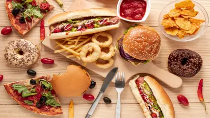 Top view of fast food including burgers, fries, pizza, donuts, and chips — symbolizing ultra-processed foods linked to brain aging.