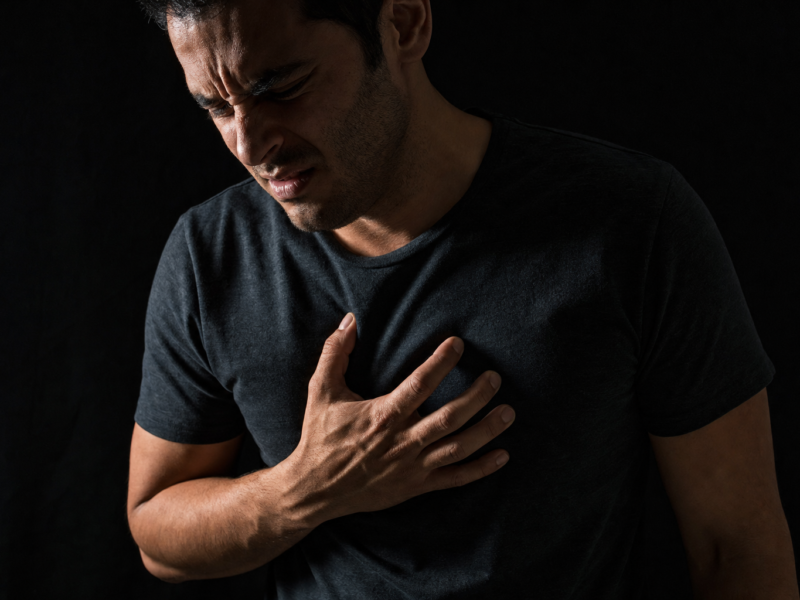 Person experiencing chest discomfort in a dark moody setting, representing acid reflux and GORD symptoms