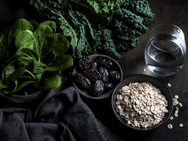 Dark moody image of fiber-rich foods like fruits, vegetables and water, representing natural constipation relief