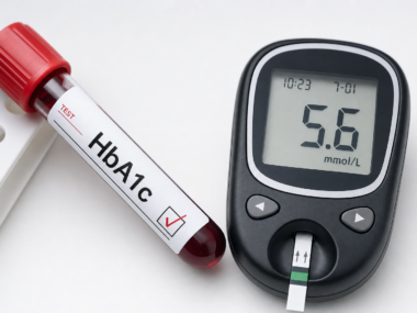 HbA1c blood test tube and glucose meter on white clinical surface representing blood sugar monitoring