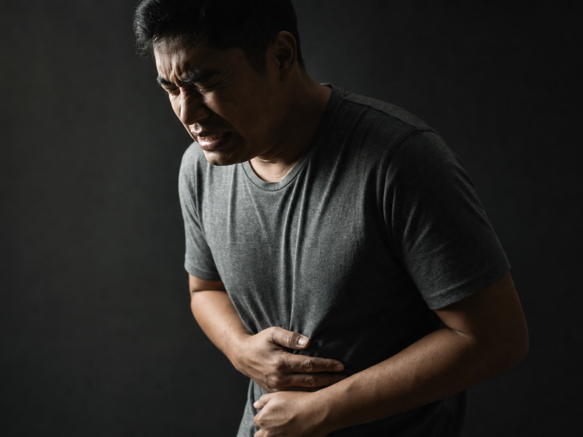 Person holding their stomach in discomfort in a dark moody setting, representing IBS symptoms