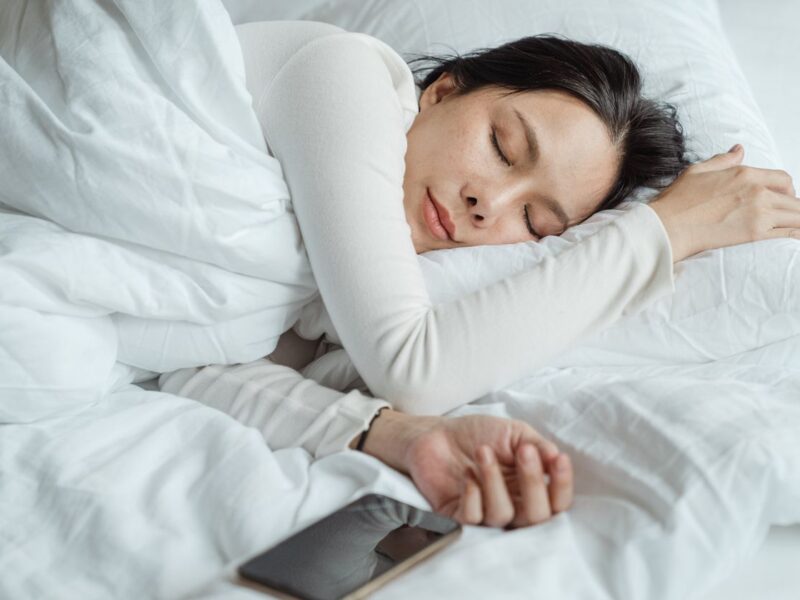 Woman sleeping in bed near smartphone with screen glow at night